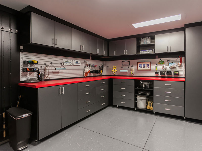 Trendy black garage storage cabinets and red countertop make this custom workbench with black uppers a handsome garage system.