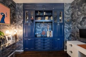 A blue cabinet surrounded by a plant pattern wallpaper